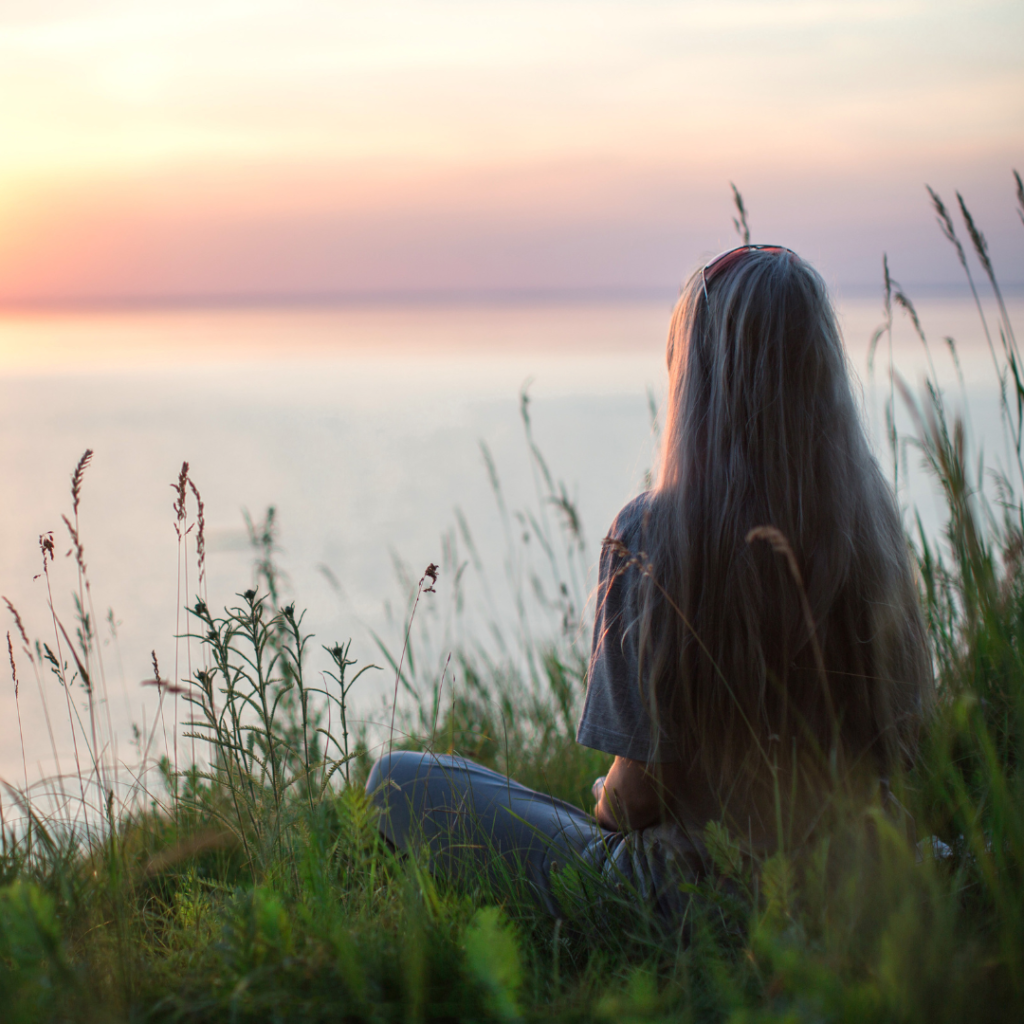 Photo of Woman Sitting on Grass During Golden Hour