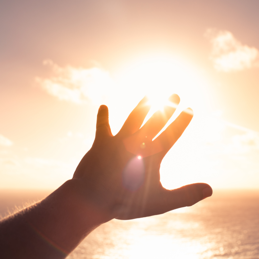 Hand up reaching out to the sunlight.