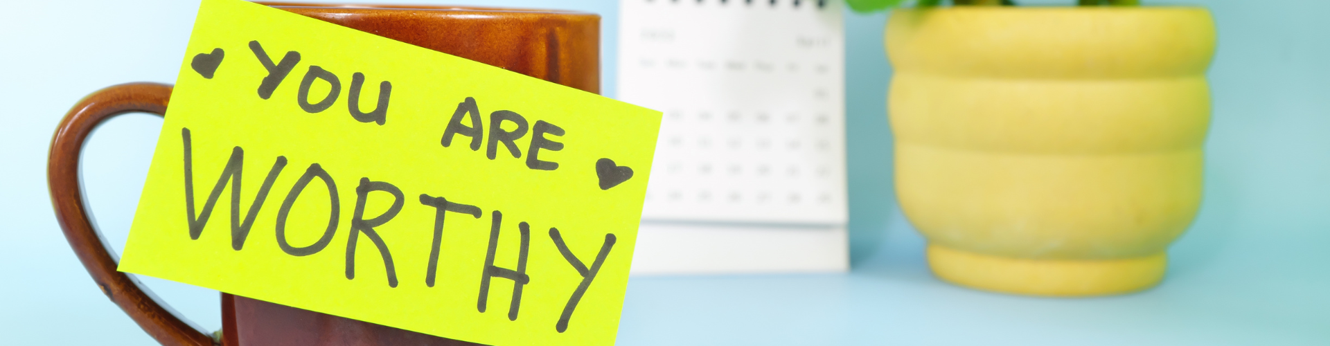 You are worthy words of encouragement and trust concept. Selective focus of a cup of coffee with handwritten bright paper message note.