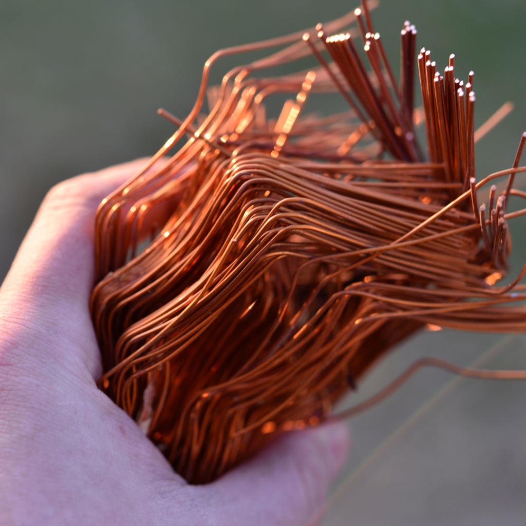 A bundle of copper wire in his hand. Copper scrap. Shiny red copper wire.