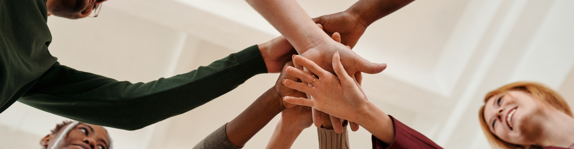 People Putting Hands Together in Act of Motivation and Smiling